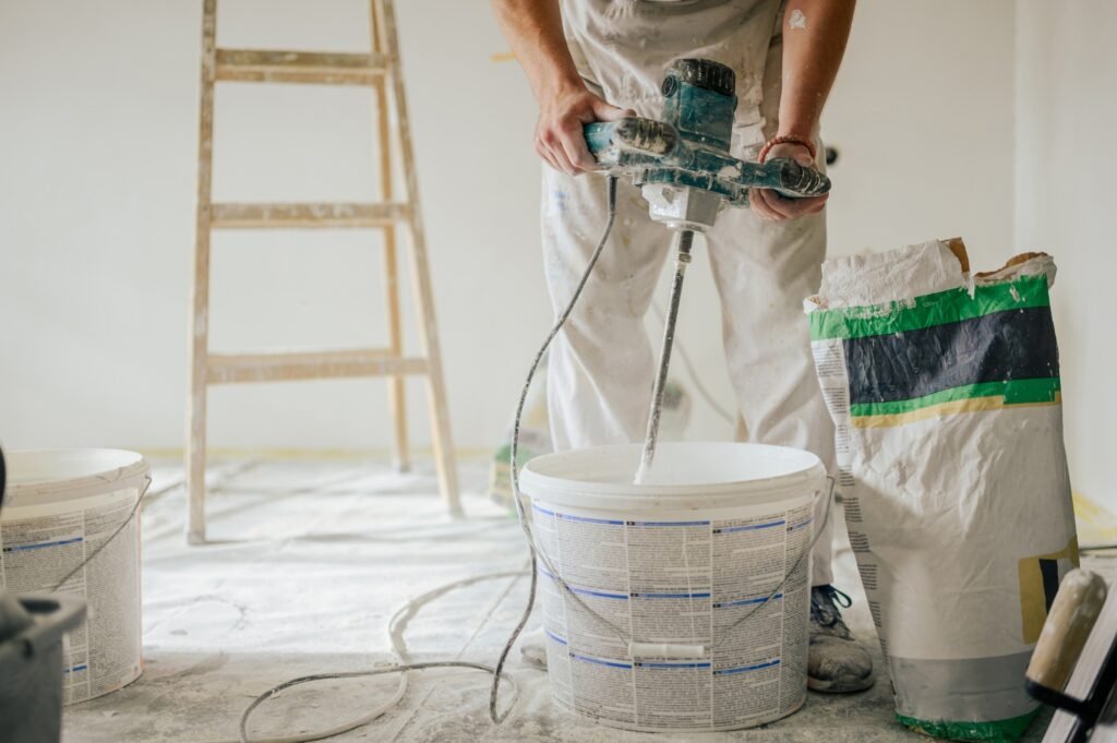 Worker's hands using mixer for making plaster for skim coating walls.