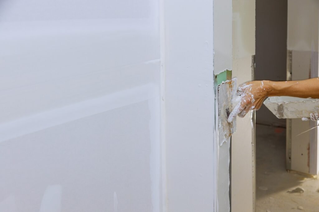 Worker spreading coating plaster the walls with putty